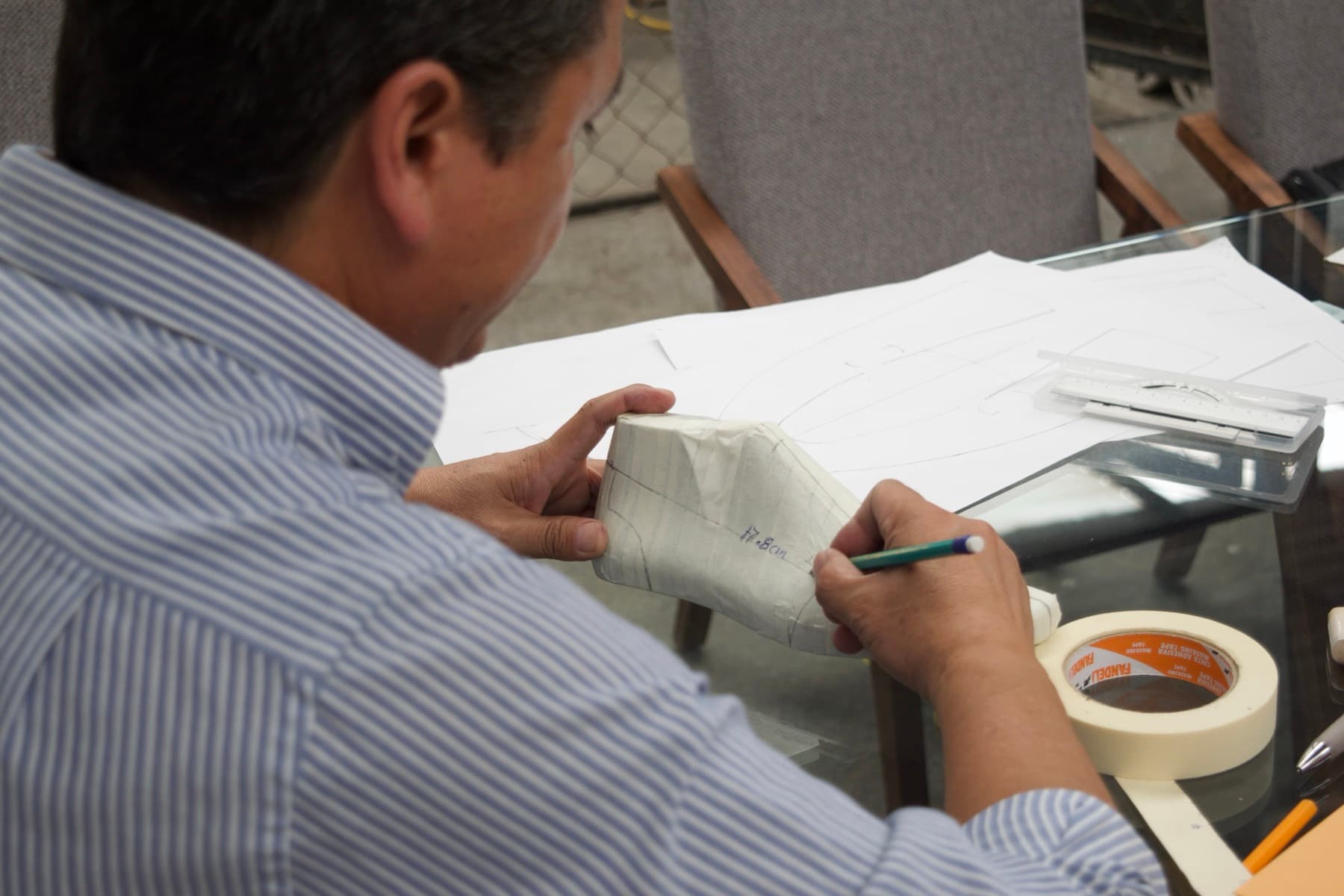 Craftsman drawing footwear patterns by hand