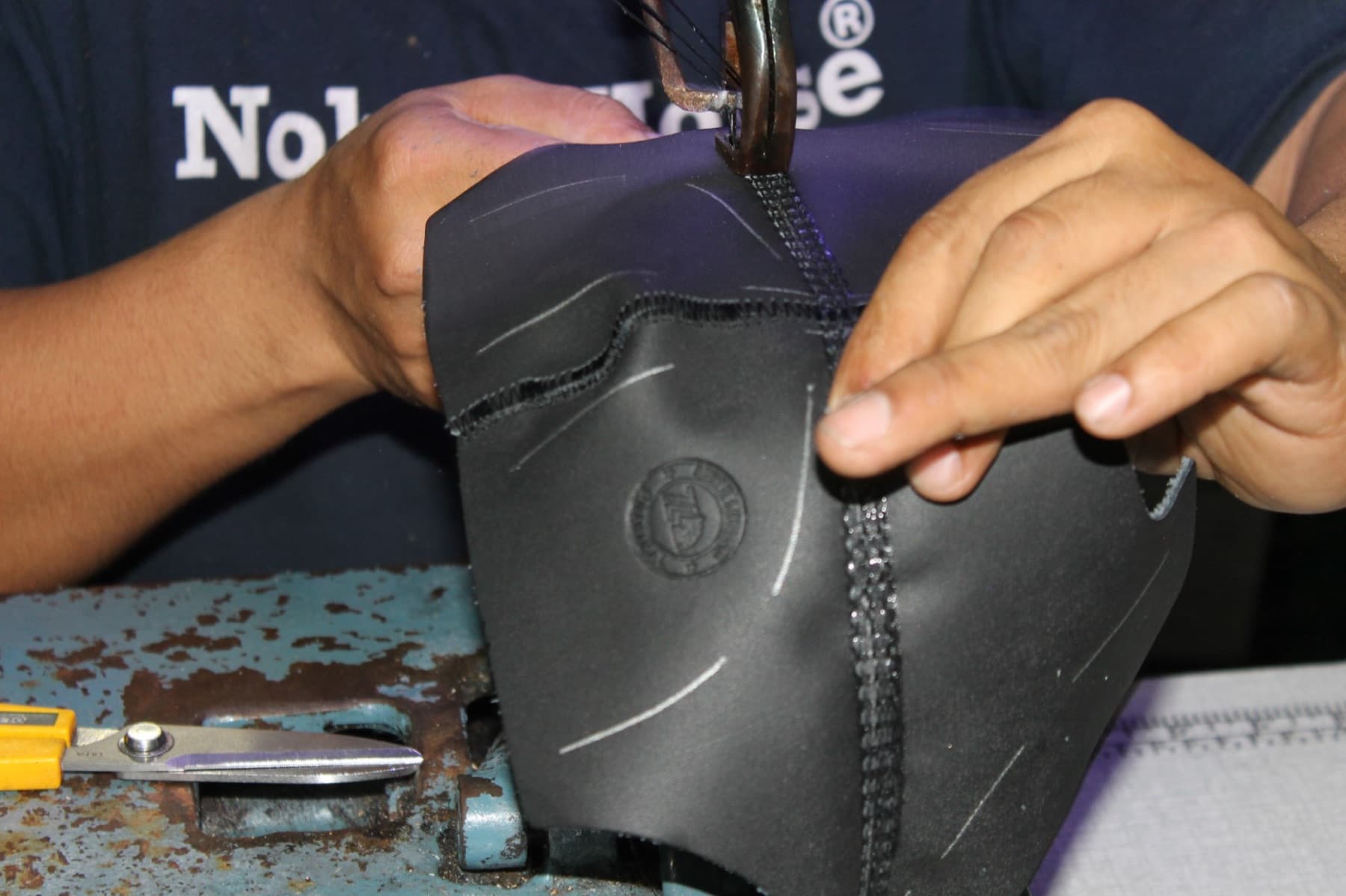 Hands of a craftsman stitching a piece of footwear